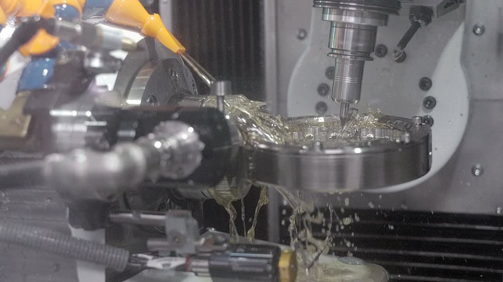 Hochpräzise CAD/CAM-Frästechnik unter Kühlung bei der Bearbeitung eines Titanblocks zur Herstellung von Implantatgerüsten. Digitale Fertigung bei CCDE in Mönchengladbach.